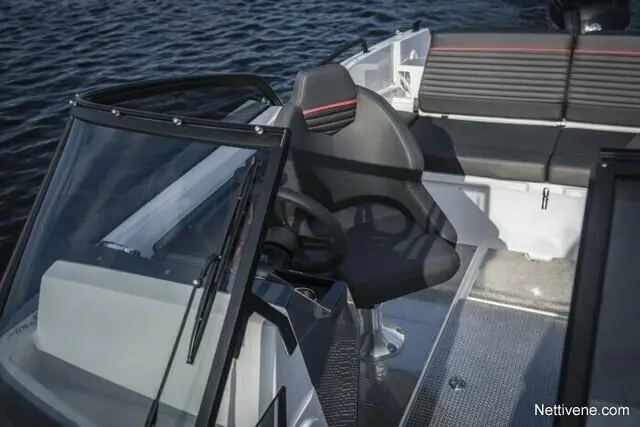 A modern boat's cockpit featuring a sleek adjustable captain's chair, glass windshield, and padded rear seating.